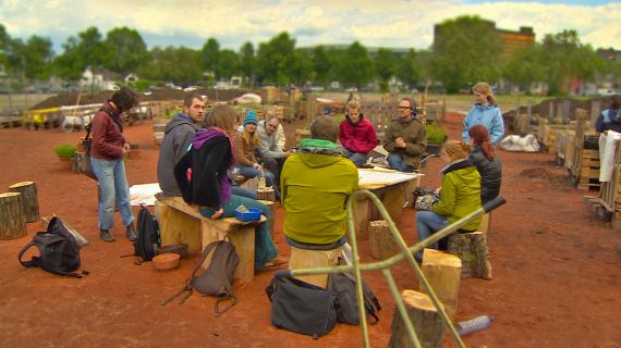 Menschen sitzen draußen um einen Tisch herum