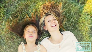 Mutter und Tochter liegen lachend im Gras