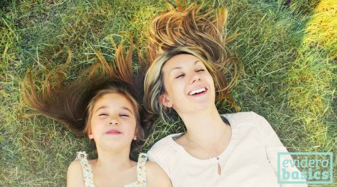 Mutter und Tochter liegen lachend im Gras