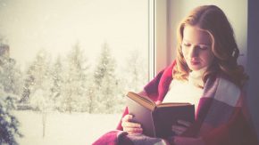 Glückliche Frau liest ein gutes Buch im Winter