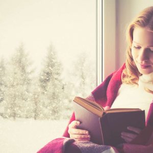 Glückliche Frau liest ein gutes Buch im Winter