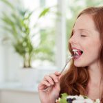 Frau isst gesunden Salat: Abnehmen mit Rohkost