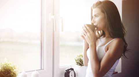 Eine Frau trinkt ein heißes Getränk zum Wachwerden am Morgen