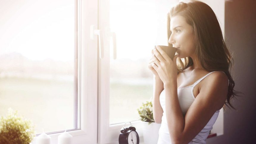 Eine Frau trinkt ein heißes Getränk zum Wachwerden am Morgen