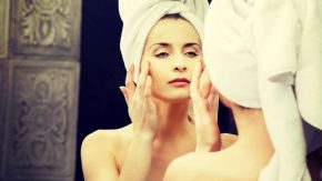 Frau pflegt ihre Haut vor dem Spiegel - Schöne Haut ab 30