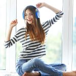 Eine junge Frau hört Musik, singt und ist glücklich