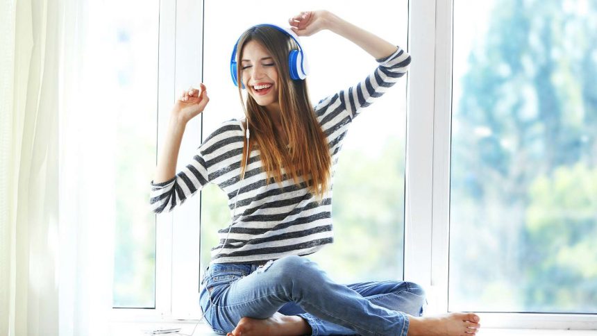 Eine junge Frau hört Musik, singt und ist glücklich