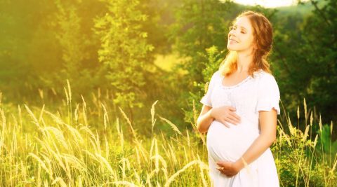 Glückliche schwangere Frau in der Natur