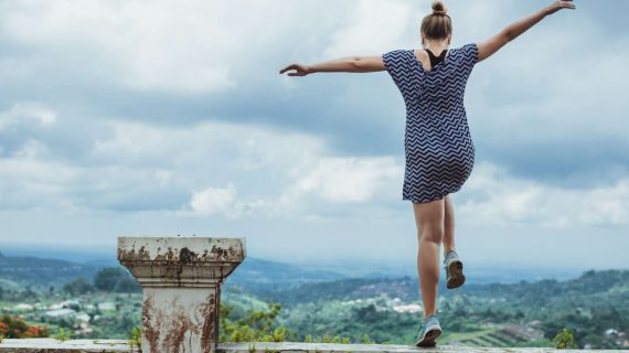 Junge Frau springt frei und leidenschaftlich über eine Mauer