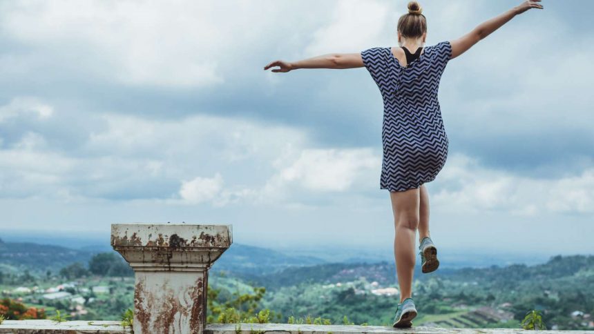 Junge Frau springt frei und leidenschaftlich über eine Mauer