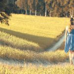 Frau läuft im Sommer über einen Feldweg und lässt alle Selbsttäuschungen hinter sich