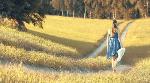 Frau läuft im Sommer über einen Feldweg und lässt alle Selbsttäuschungen hinter sich