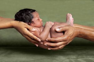 Baby geborgen in den Händen der Eltern