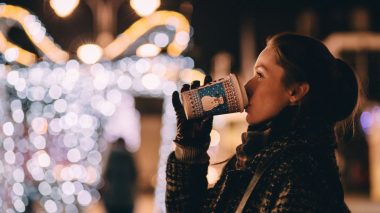 Frau trinkt Glühwein auf dem Weihnachtsmarkt