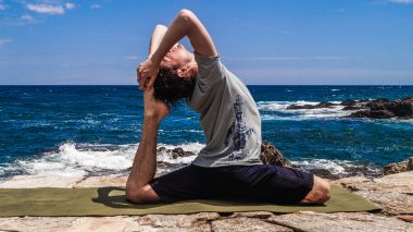 Mann macht Yoga am Strand