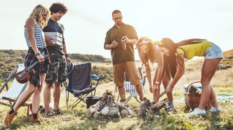 Freunde bereiten beim Campen ihr Abendessen zu